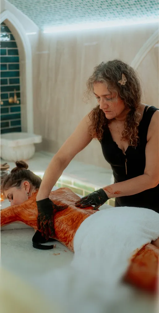 Frau erhält eine Ganzkörpermassage mit einer braunen Paste in einem stilvollen Spa.