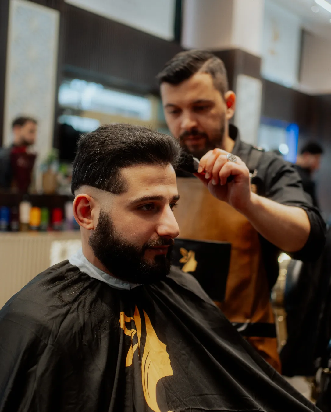 Friseurbart, der einem Mann mit schwarzem Haar und Vollbart mit einem Pinsel Haare entfernt.