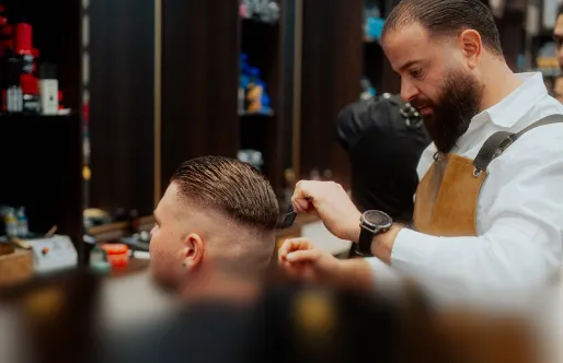 Barbier schneidet Haare eines Mannes in einem Salon mit professioneller Ausrüstung.