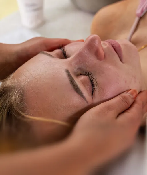 Frau mit geschlossenen Augen, die eine entspannende Gesichtsmassage erhält.
