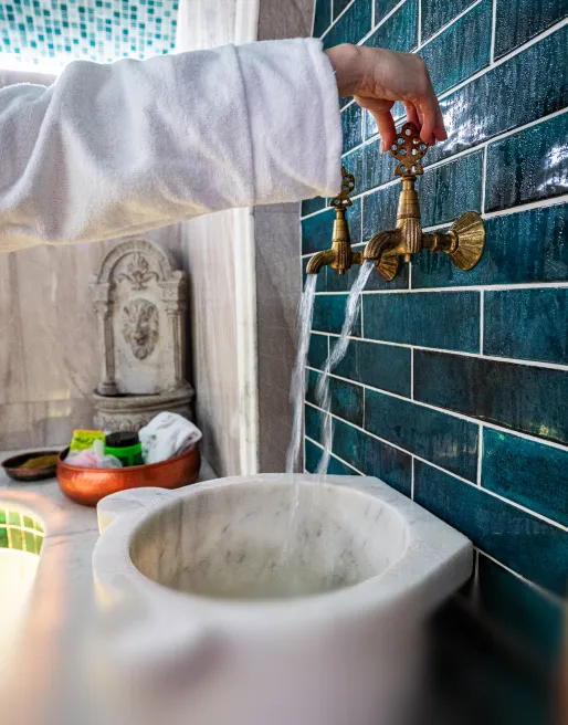 Moderne Frisierplätze mit schwarzen Ledersesseln und Waschbecken in einem stilvollen Salon mit beleuchteten Regalen.