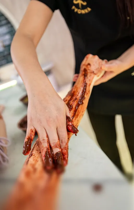 Eine Person trägt eine blutige Gipsform an einem Arm, wobei Hände und Unterarm mit Kunstblut bedeckt sind.